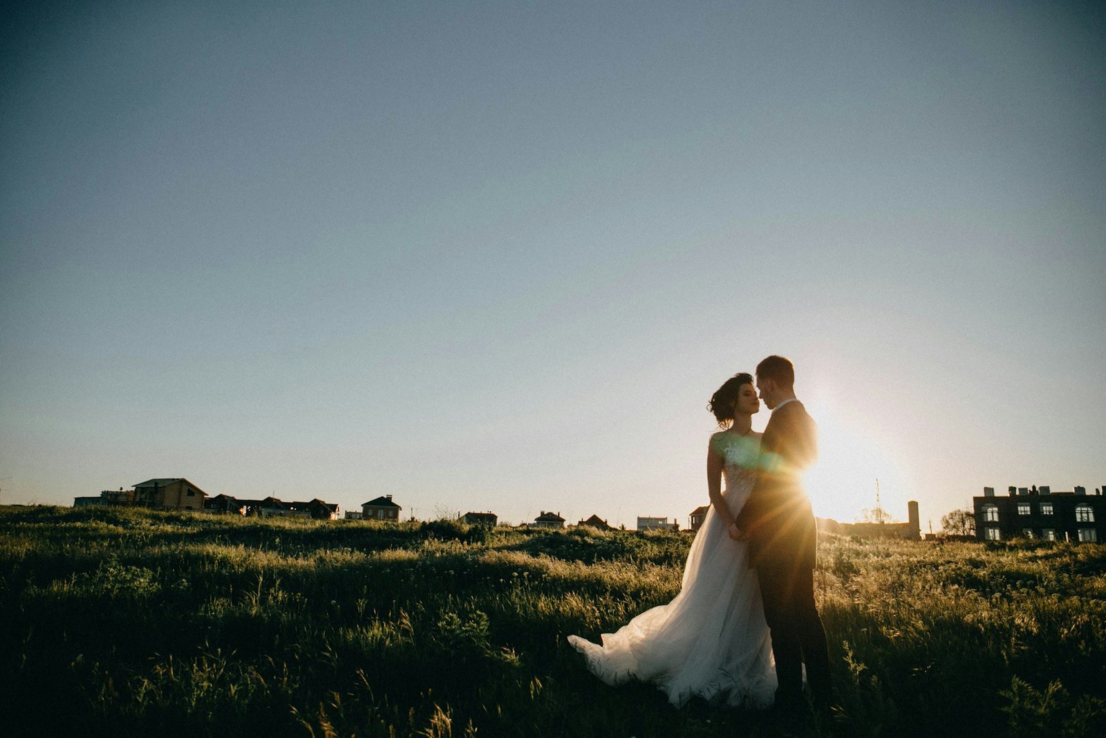 Bride and groom sharing an intimate moment in a sunlit meadow, evoking a cinematic countryside wedding feel.