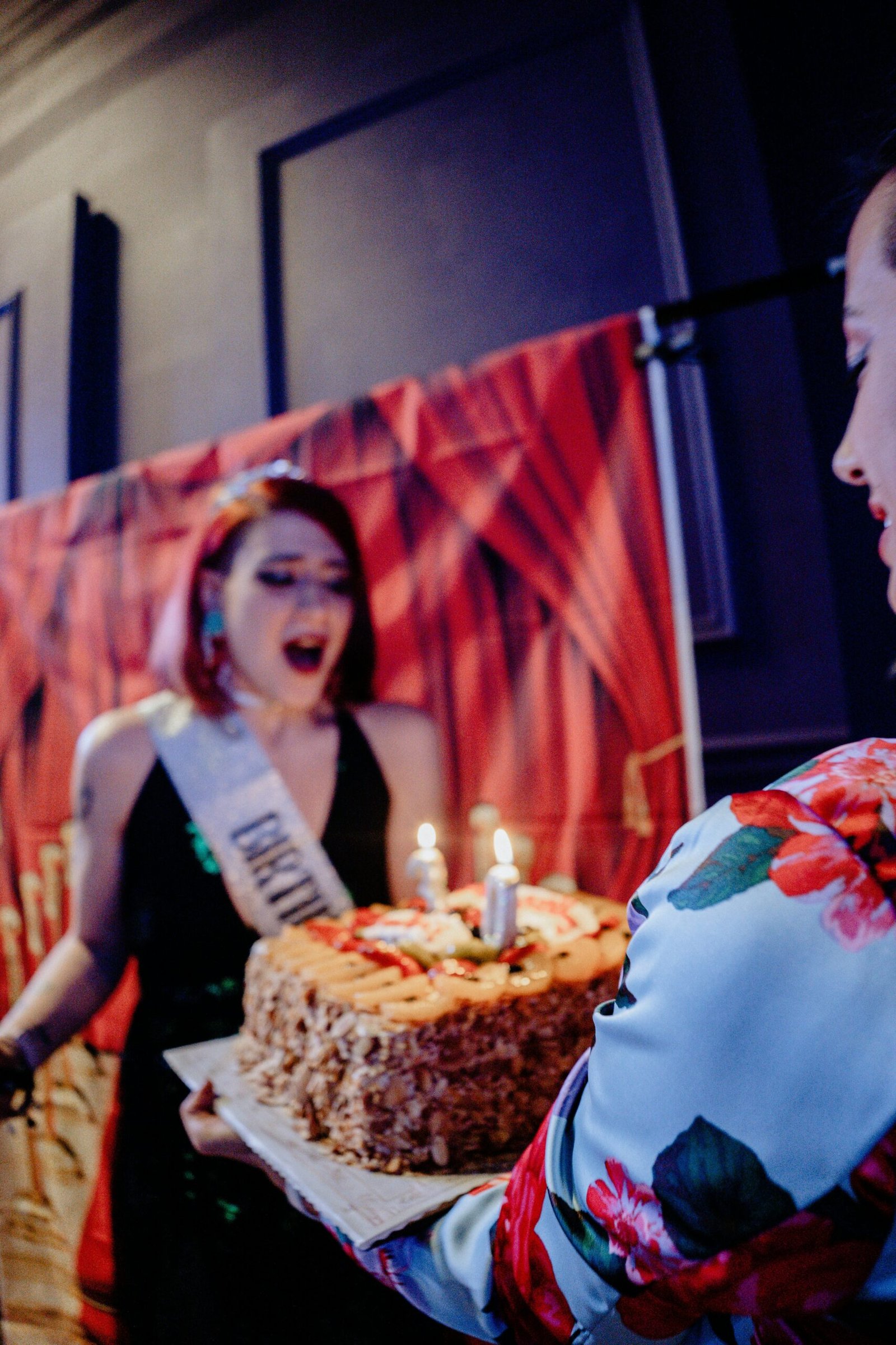 Mini Party Package | Memorable Birthday Moments by Wave Studio Birthday celebration with a young woman wearing a sash, surprised by a lit birthday cake.