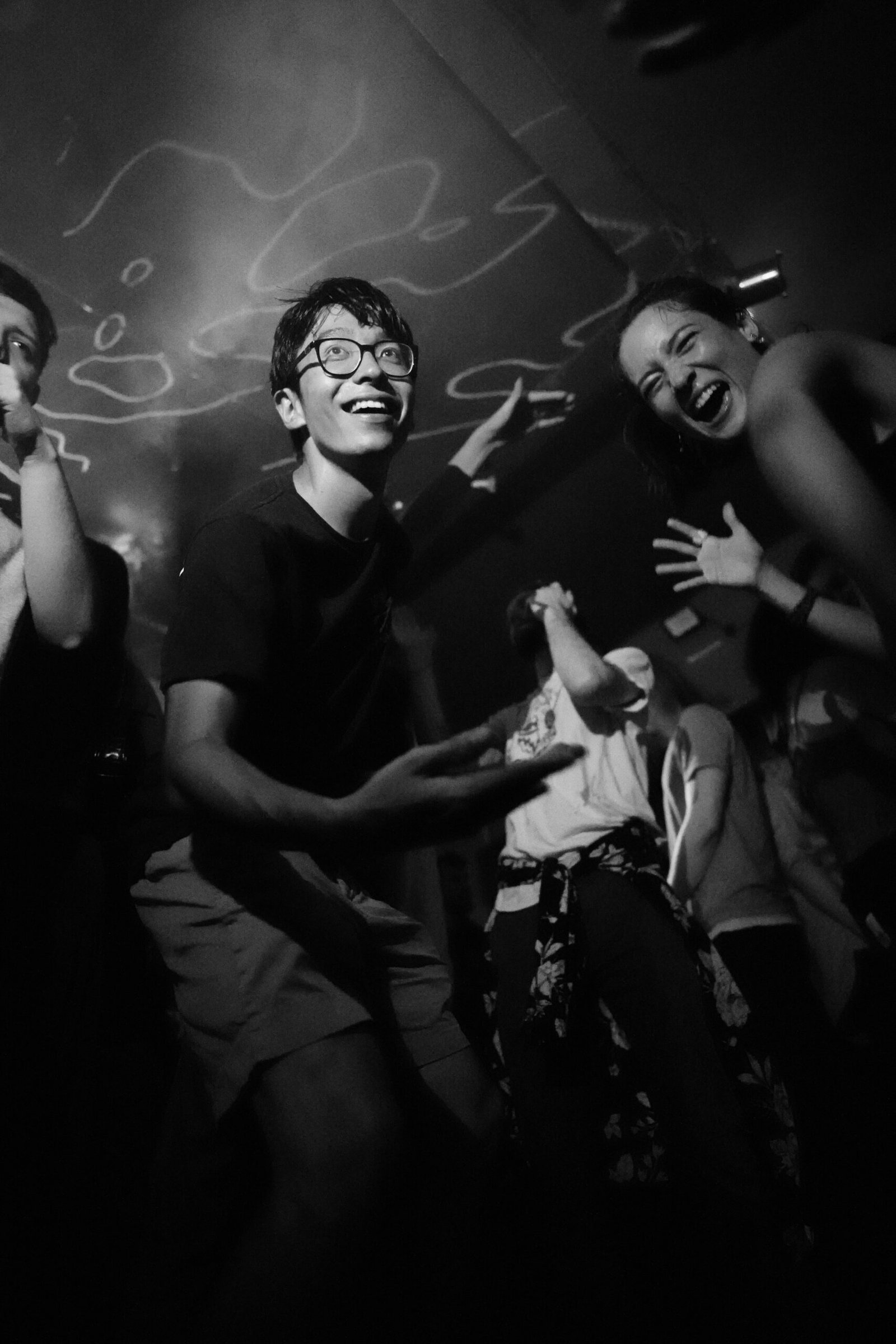 Celebration Package | High-Energy Event Photography by Wave Studio Black-and-white shot of a man dancing with friends at a lively event, capturing genuine laughter and excitement.